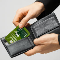 Waterfall D-Mannose sachets lifestyle image with a young man holding a wallet and pulling out a Waterfall D-Mannose sachet from the credit card section of the wallet.